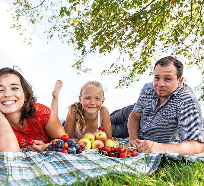 Familie liegt auf der Wieder vor Ihnen Schale mit Obst