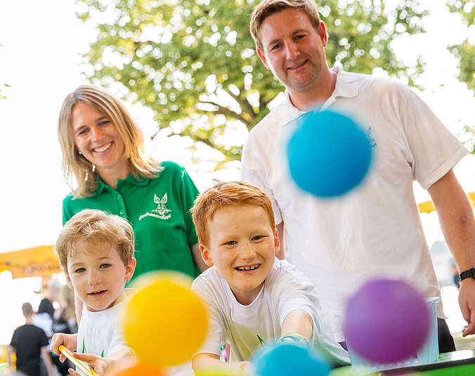 Kinder spielen mit Eltern an Glücksbude