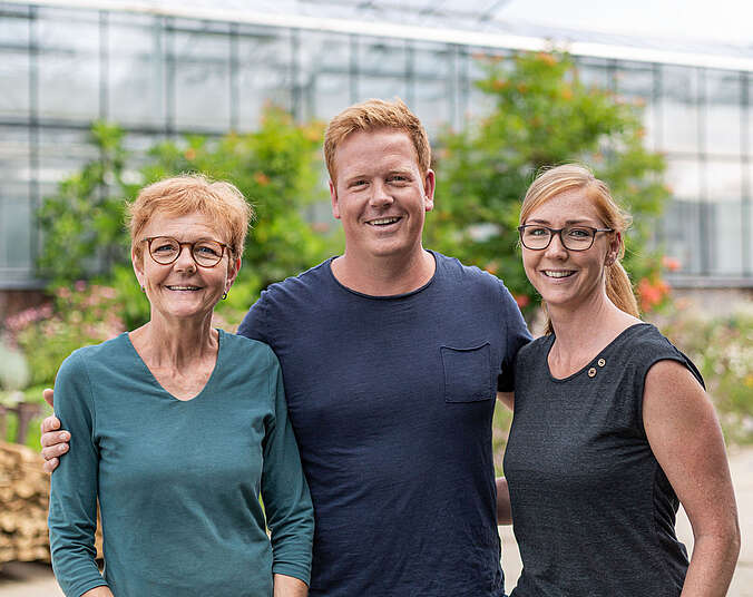 3 Personen vor Gewächshaus