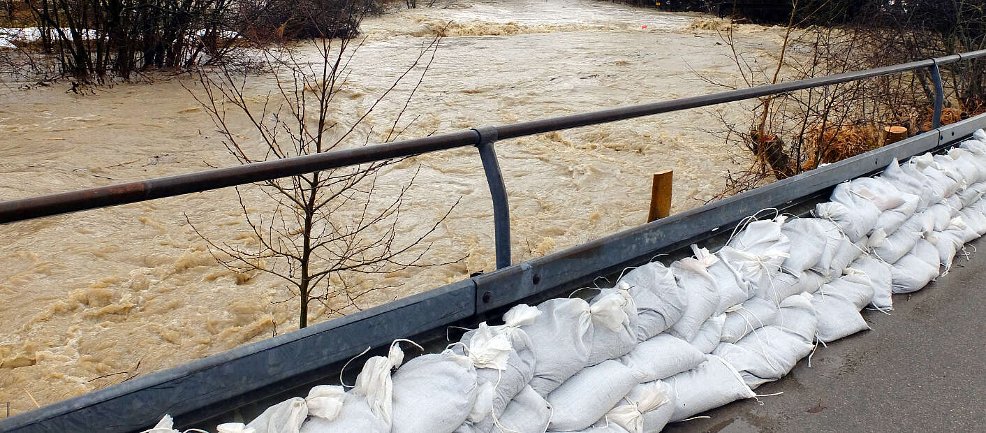 Fluss mit Hochwasser, Sandsäcke