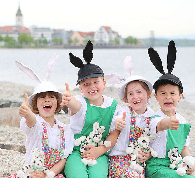 vier Kinder sitzen mit Seehasohren und Seehaskuscheltieren