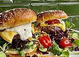 Lecker angerichteter Burger mit Tomaten, Salat und geschmolzenem Käse.