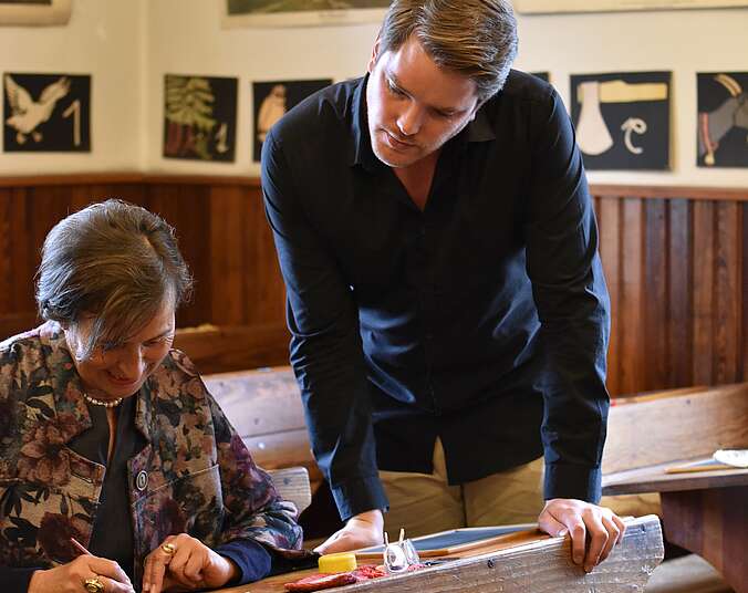 Museumsführer erklärt einer Dame das Schreiben auf der Schiefertafel