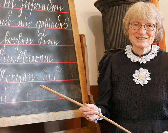 Eine Frau ist verkleidet wie eine Lehrerin um 1900