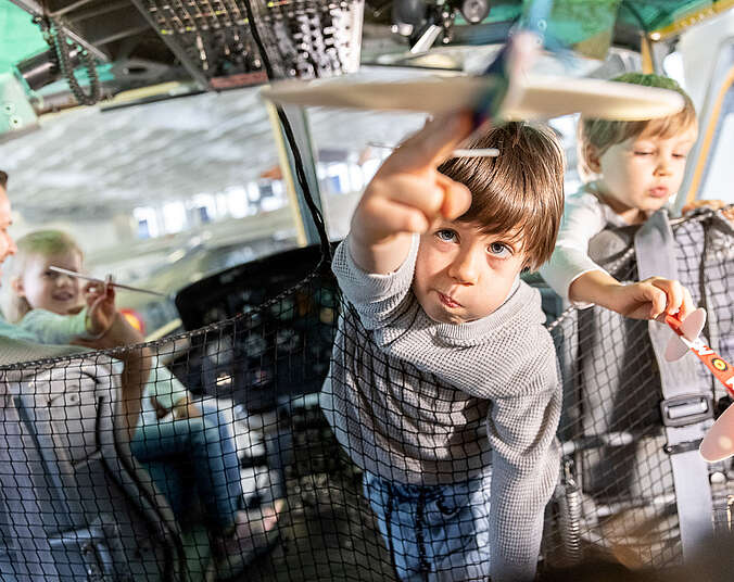 Kind im Cockpit zeigt auf Miniaturflugzeug