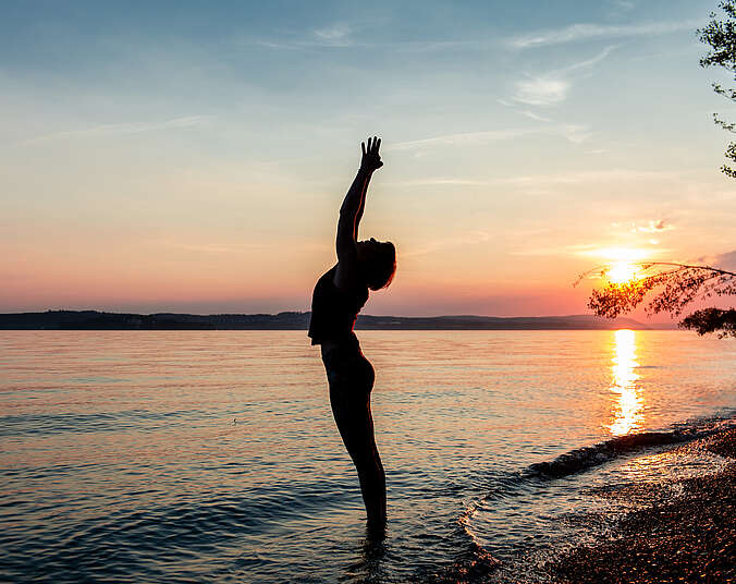 Person in Yogaposition am See vor Sonnenuntergang