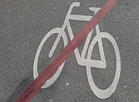 weißes Fahrrad mit roten Balken durchgestrichen auf Asphalt