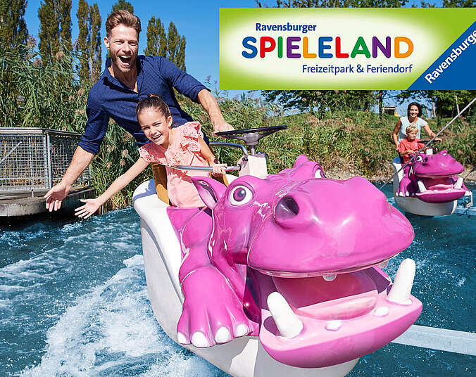 Mann und Kind in einer Wasserbahn. Beide befinden sich in einem rosa Nilpferd