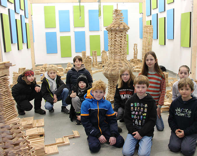 Mädchen und Jungen vor hohen Türmen aus Holz