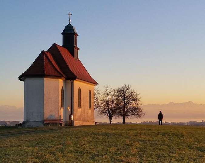 Kapelle im Abendlicht vor Bergkulisse