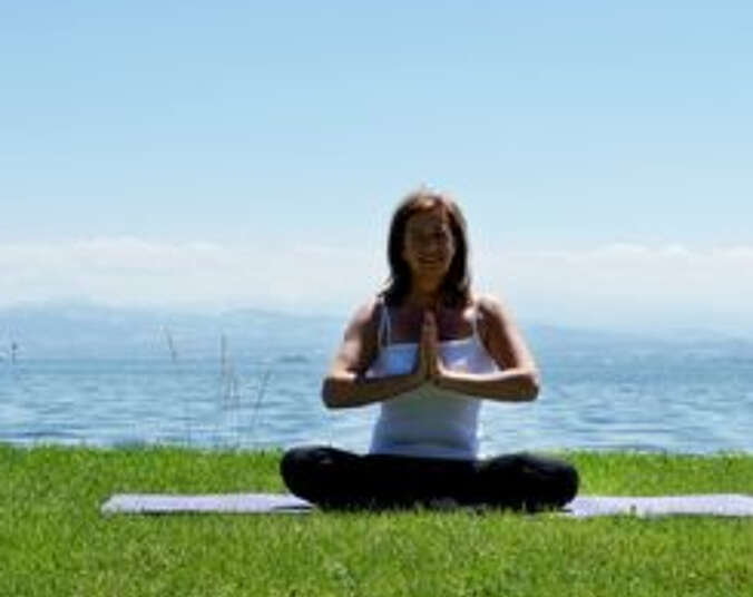 Frau in Yoga-Pose am See