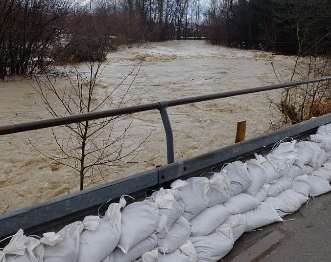 Sandsäcke entlang von Leitplanke sollen Hochwasser von Fluss zurückhalten