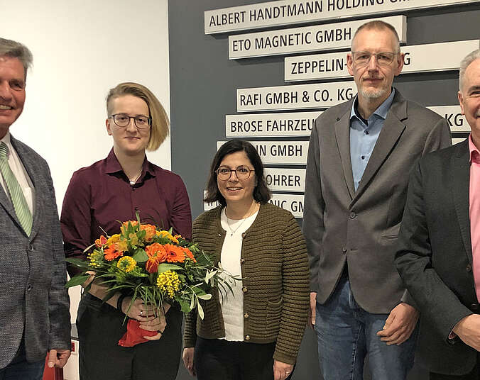 Drei Männer und zwei Frauen, ein mit einem Blumenstrauß.