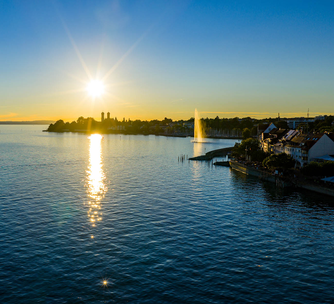 Sonnenuntergang in Friedrichshafen mit Seefontaine vor Uferpromenade und Schloss