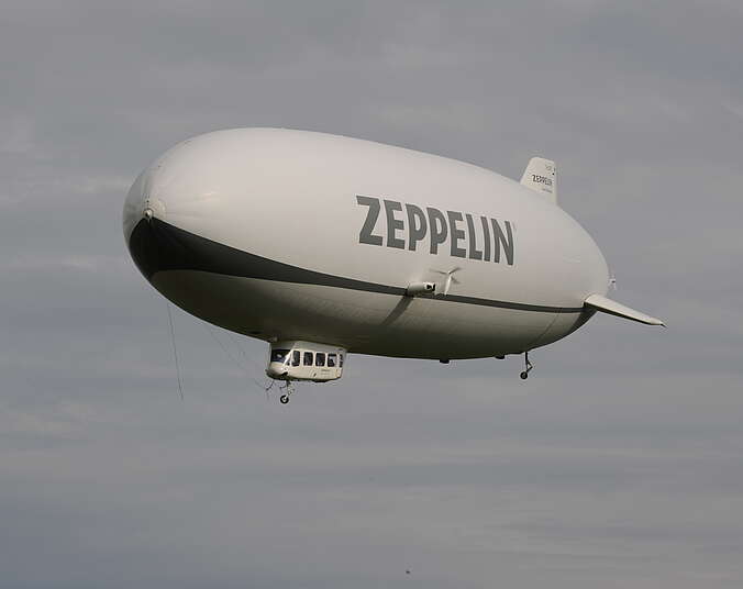 Weißer Zeppelin in der Luft mit dichten weißen Wolken im Hintergrund