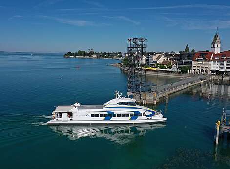Katamaran bei der Einfahrt im Hafen Friedrichshafen im Hintergrund Moleturm und Uferpromenade