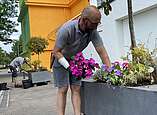 Der Chef persönlich, Florian Mayer, setzt frische Blumen in die Leihgefäße, die den Sommer über den Platz vor dem Schulmuseum zieren.