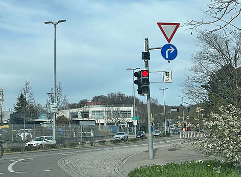 Straßenkreuzung mit Ampelmast und Schildern